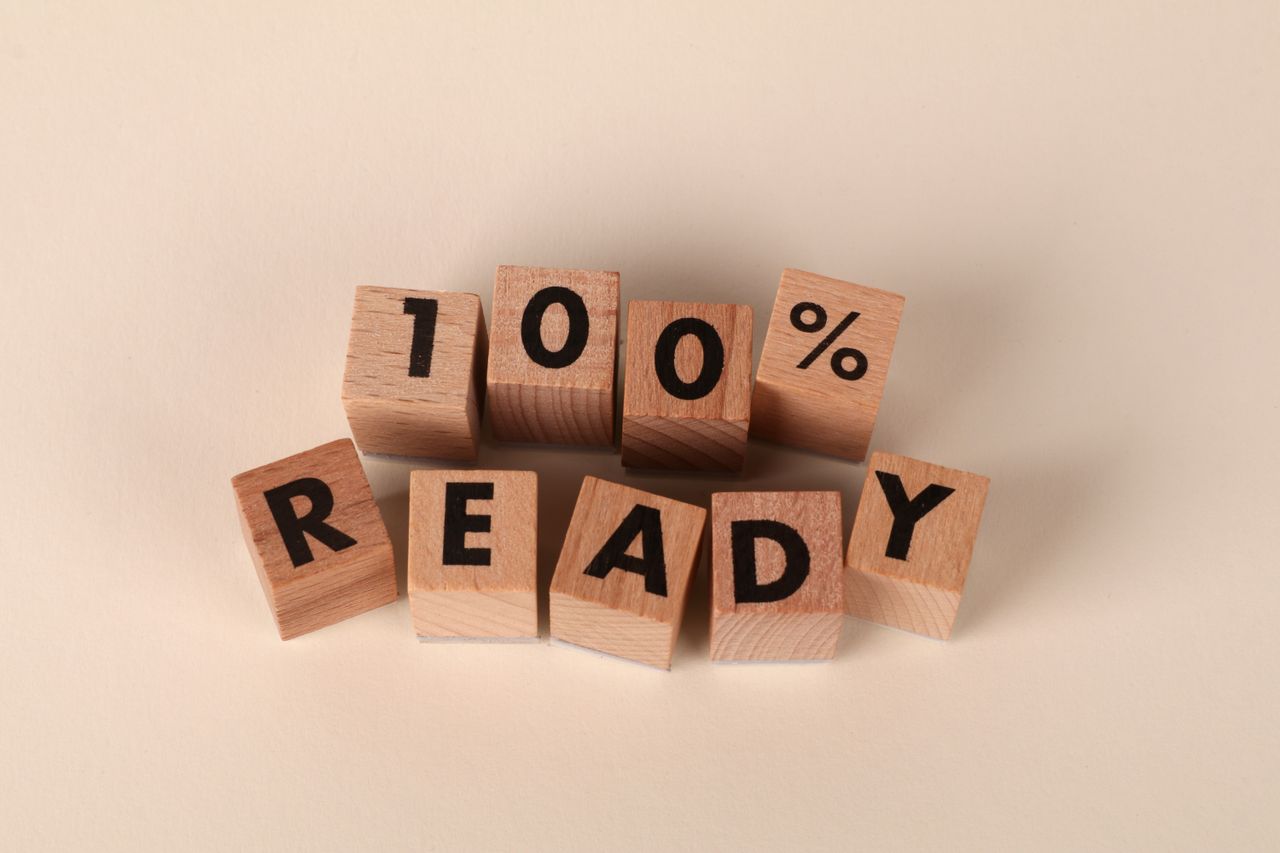 about-img Wooden blocks arranged to show the text '100% Ready' on a neutral background, symbolizing preparedness and confidence.