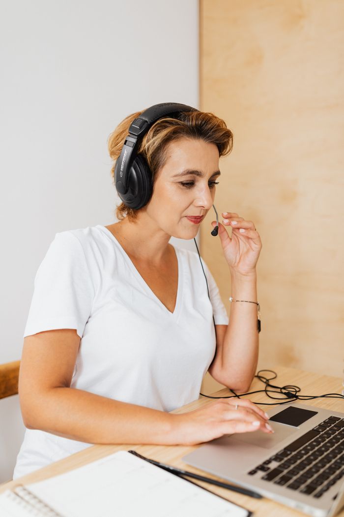 hero-gallery-02 Professional woman using a laptop and headset for remote work, engaged in video conferencing