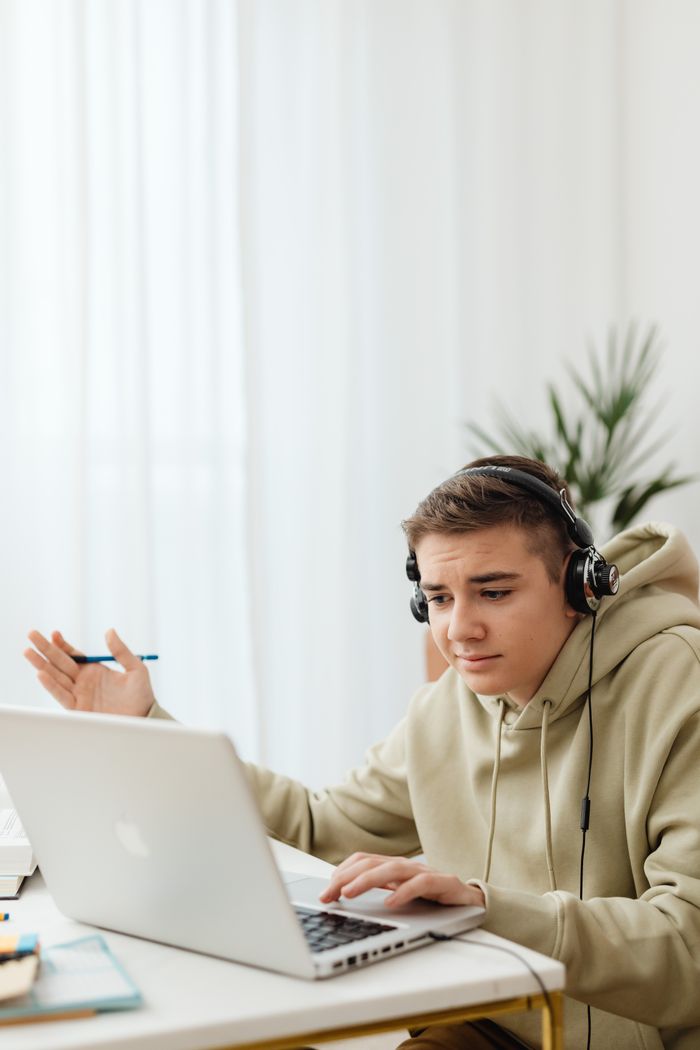 hero-gallery-04 Teenager in hoodie using laptop for online learning at home.