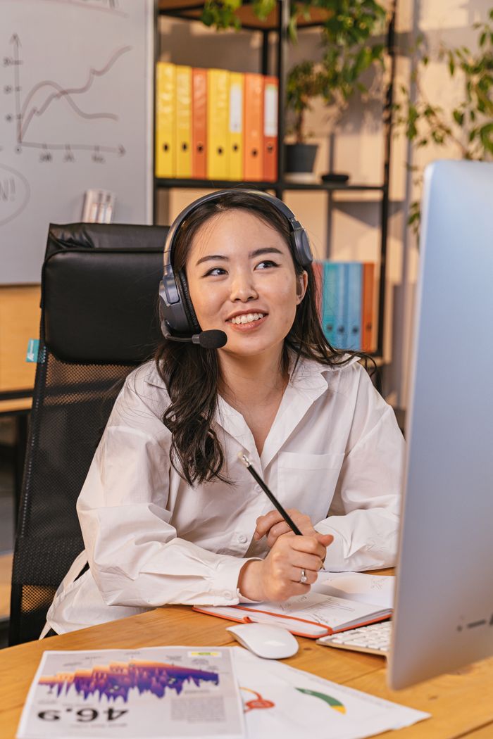 programs-02 Professional woman with headset working at desk, engaged in a virtual meeting.